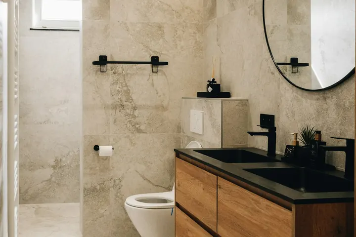 Baño reformado con revestimiento de piedra y mueble de madera
