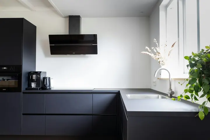 Cocina reformada con muebles negros y encimera en L